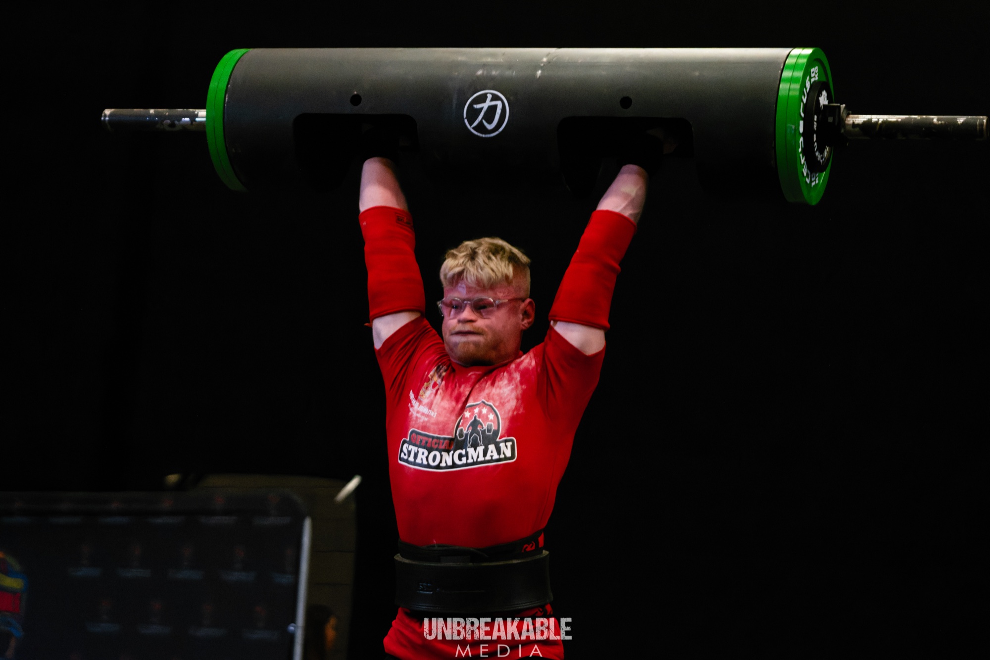 Michael locking out a log press overhead at a strongman competition, 80kg class